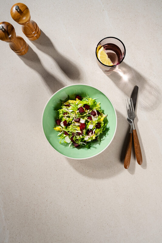 Bietensalade met feta in turquoise bord en bestek met houten handvat