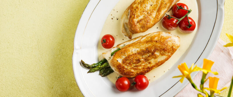 Met groene asperges gevulde kipfilet in roomsaus met gepofte cherrytomaten